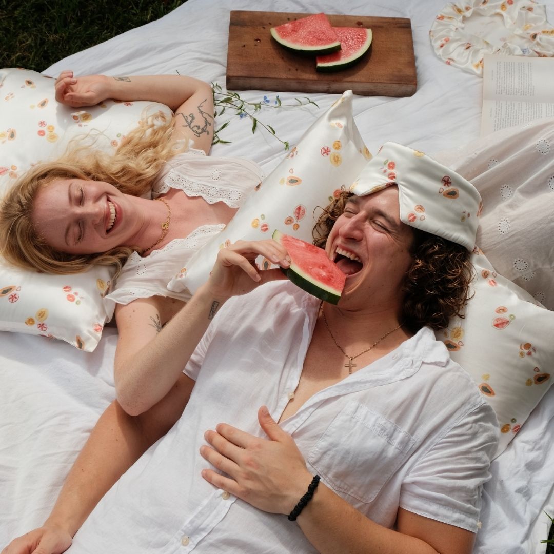 Silk pillowcases in a fruit pattern with models eating watermelon