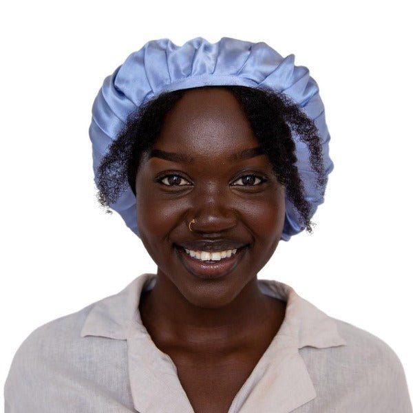 A woman wearing a white silk sleeping cap with a light blue bonnet